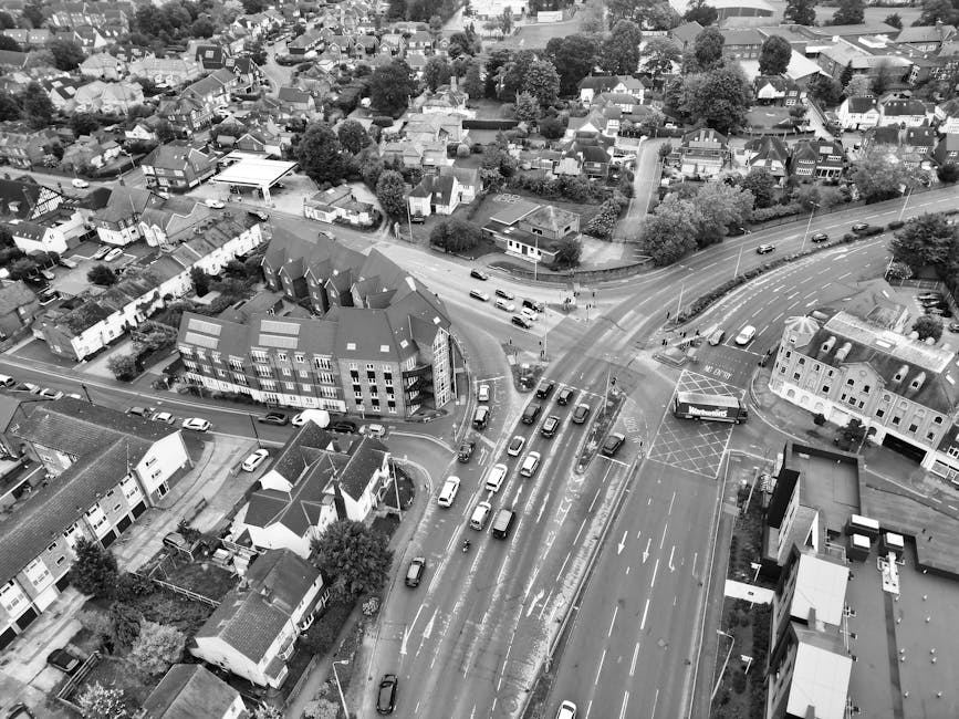 Aerial black-and-white photograph of a residential urban area showing densely packed houses, streets, and trees. A railway line runs diagonally through the center of the image, with adjacent roads int