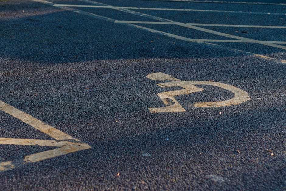 Close-up view of a parking space on a tarmac driveway with the number '22' painted in white, showing signs of wear and slight fading. The space is adjacent to other marked parking areas with partially visible lines and numbers. The scene is outdoors, with natural lighting casting slight shadows on the textured surface. This setting is typical of a residential or city parking lot used during home relocations or furniture transport. The image reflects the environment where Man with Van Rainham might load or unload belongings for house removals on Wennington Road, highlighting practical aspects of moving logistics such as parking arrangements and access points.